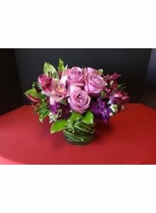 low arrangement with purple flowers, purple roses, orchids, alstromeria and stock