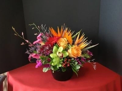 Green orchids, purple roses and birds of paradise with barries in a vase